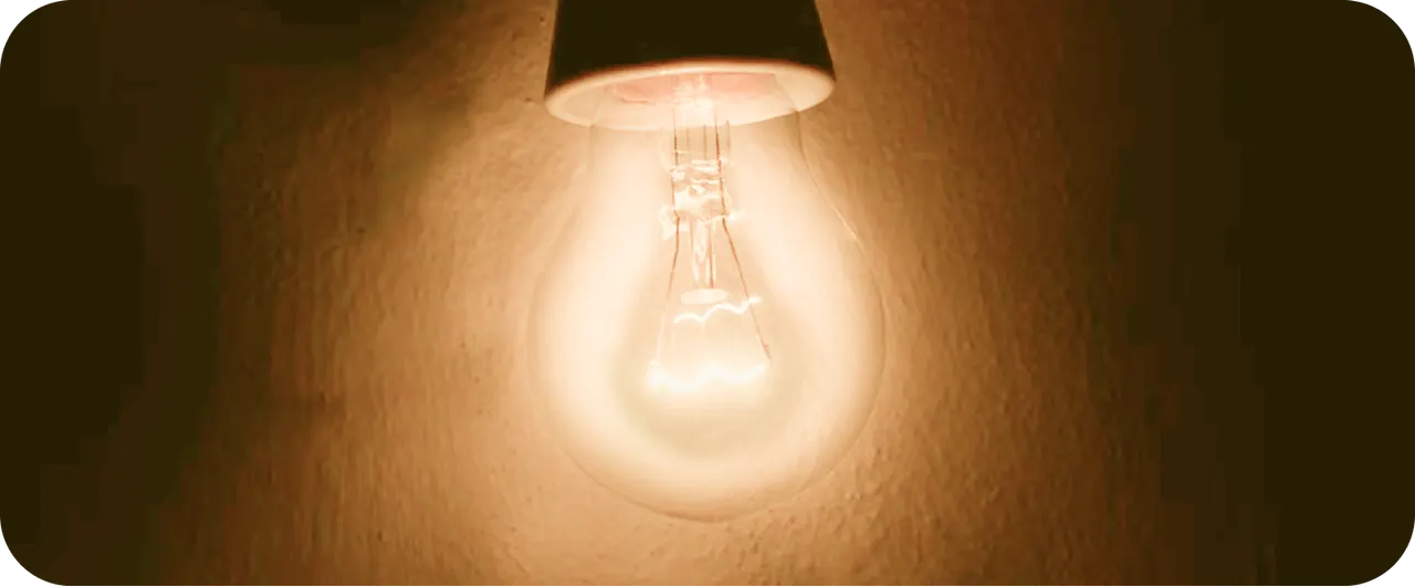 A glowing incandescent light bulb on a warm wall